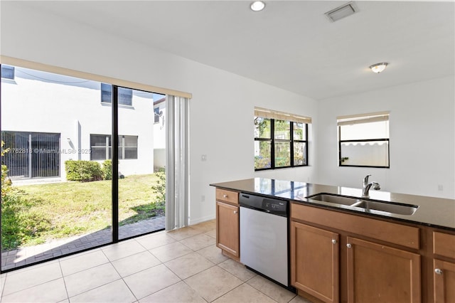 kitchen featuring visible vents, dishwasher, light tile patterned floors, brown cabinets, and a sink