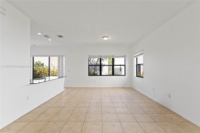 unfurnished room featuring a wealth of natural light, visible vents, light tile patterned flooring, and recessed lighting