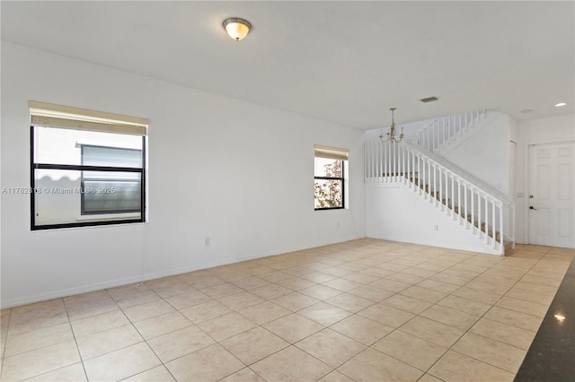 empty room featuring light tile patterned floors, visible vents, baseboards, stairs, and a notable chandelier