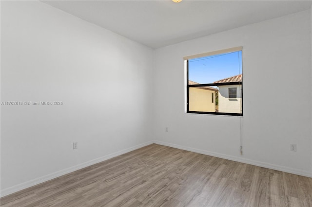 unfurnished room with baseboards and wood finished floors