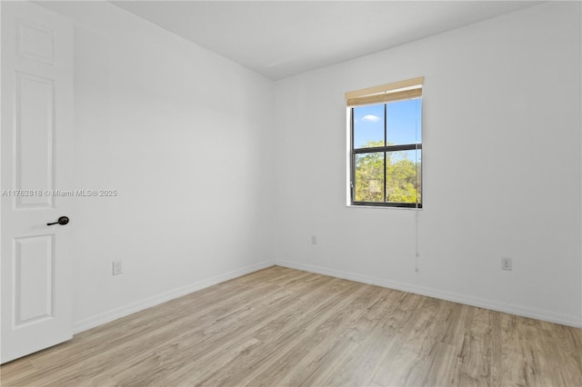 spare room featuring baseboards and light wood finished floors