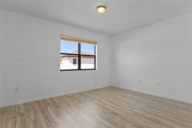 spare room with baseboards and light wood finished floors