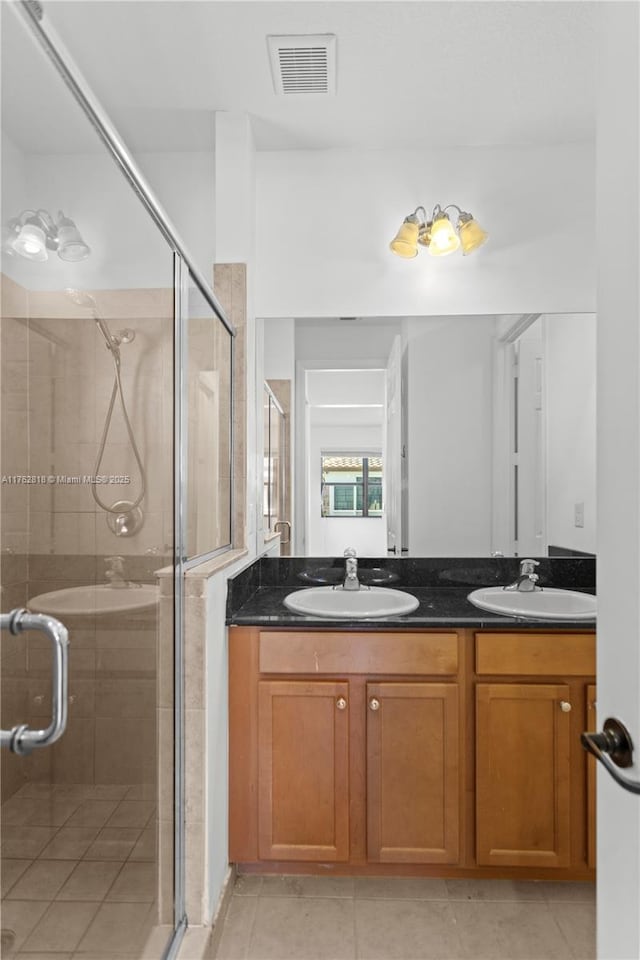 full bath with double vanity, visible vents, a stall shower, and a sink