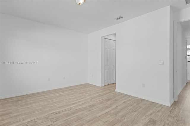 unfurnished room with visible vents, light wood-type flooring, and baseboards