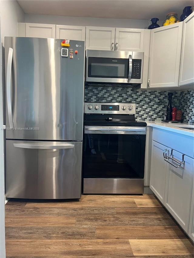 kitchen featuring wood finished floors, decorative backsplash, light countertops, appliances with stainless steel finishes, and white cabinetry