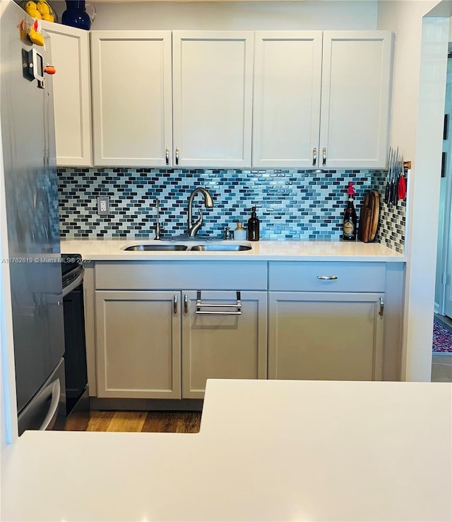 kitchen with electric stove, a sink, freestanding refrigerator, light countertops, and decorative backsplash