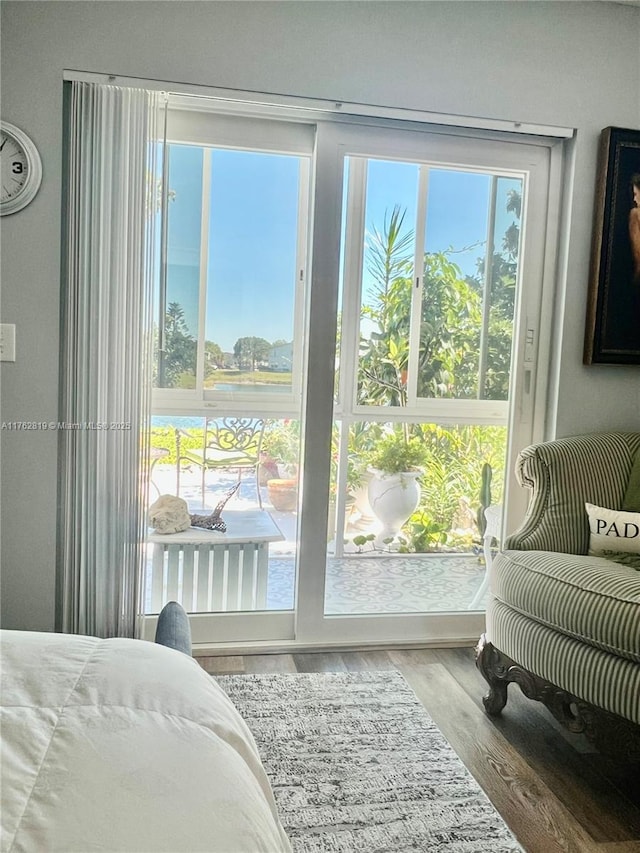 bedroom with access to outside and wood finished floors