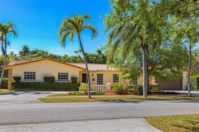 view of front of property with a tiled roof, driveway, and stucco siding