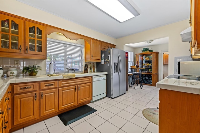 kitchen featuring dishwasher, decorative backsplash, exhaust hood, and stainless steel fridge