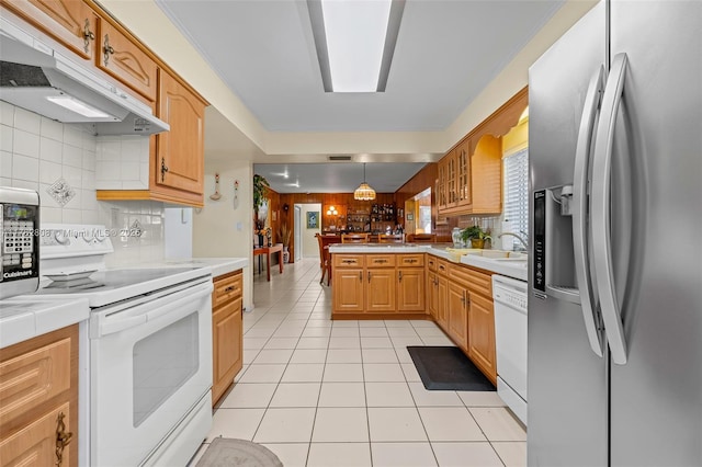 kitchen with white appliances, light tile patterned floors, a peninsula, under cabinet range hood, and backsplash