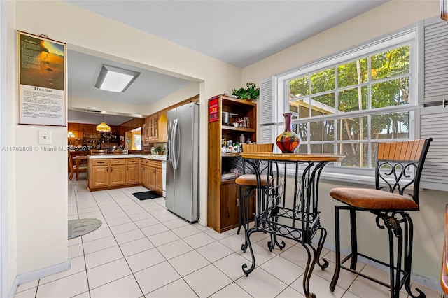 kitchen with light countertops, light tile patterned floors, and stainless steel fridge