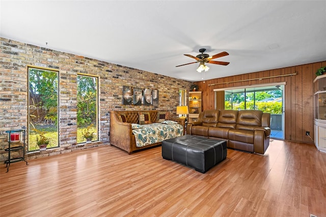 living area featuring a ceiling fan, wood finished floors, and brick wall