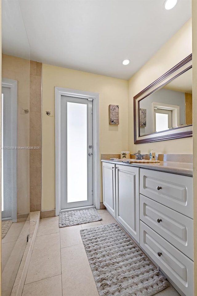 full bathroom featuring recessed lighting, tiled shower, vanity, and tile patterned flooring