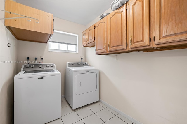 clothes washing area with light tile patterned floors, cabinet space, baseboards, and washer and clothes dryer