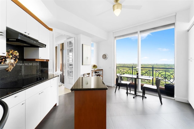 kitchen featuring under cabinet range hood, backsplash, a center island, white cabinetry, and black electric stovetop