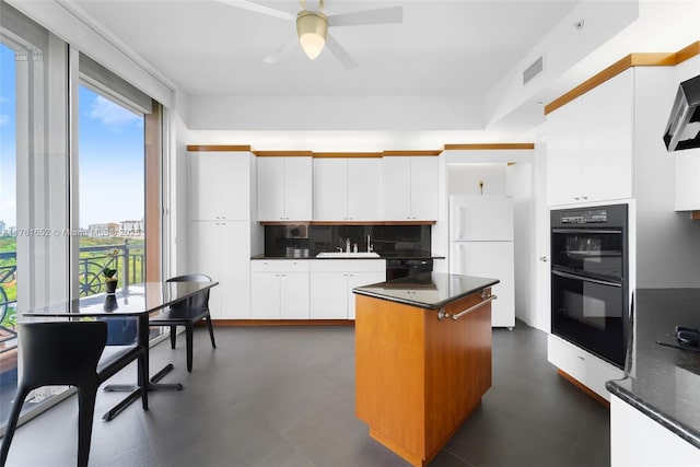 kitchen with decorative backsplash, black appliances, white cabinetry, and a center island