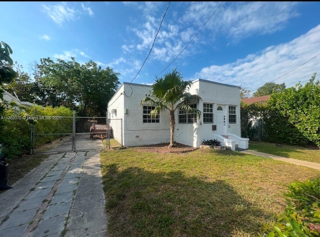 rear view of house featuring fence, concrete driveway, stucco siding, a lawn, and a gate