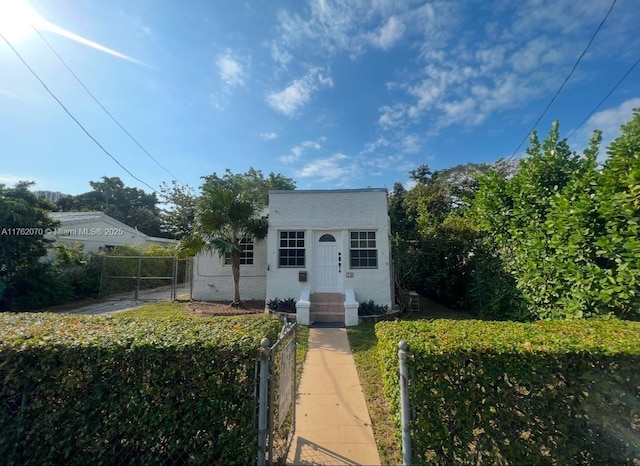 bungalow with a gate, fence, and stucco siding