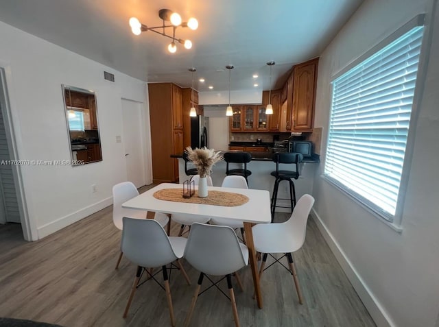 dining space with visible vents, baseboards, a notable chandelier, and wood finished floors