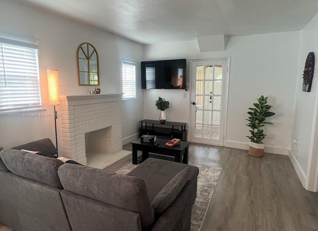 living room with a brick fireplace, baseboards, and wood finished floors