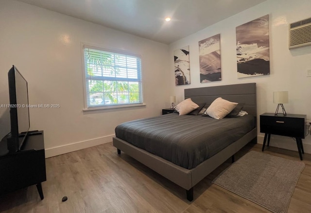 bedroom featuring a wall mounted air conditioner, light wood-type flooring, baseboards, and recessed lighting