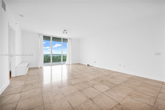 empty room featuring visible vents, baseboards, and expansive windows