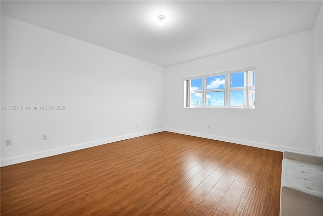 empty room with baseboards and wood-type flooring