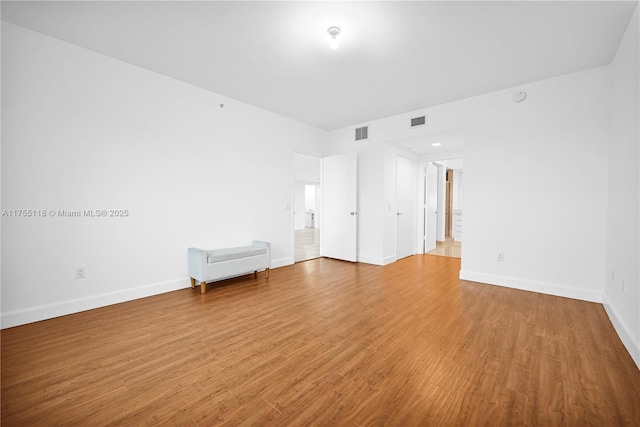 unfurnished room with visible vents, light wood-style flooring, and baseboards