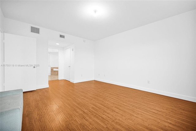 empty room featuring light wood-style floors, visible vents, and baseboards