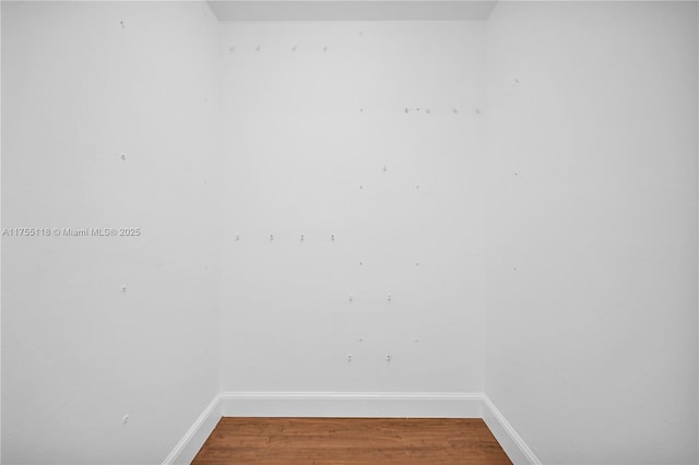 spare room with baseboards and wood finished floors