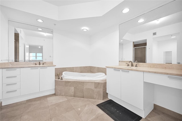 full bath with visible vents, a garden tub, two vanities, a stall shower, and a sink