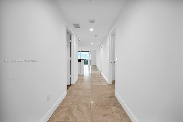 hall with recessed lighting, visible vents, baseboards, and stone finish floor