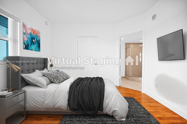 bedroom with ensuite bathroom, baseboards, and wood finished floors