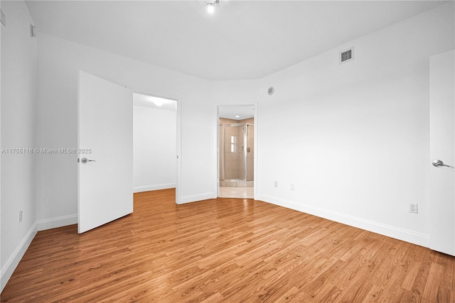 spare room with baseboards and light wood finished floors