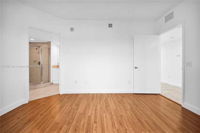 empty room with light wood-style floors, visible vents, and baseboards