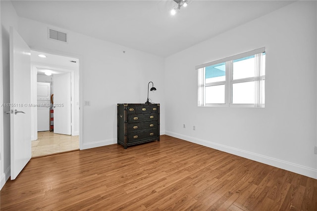 unfurnished bedroom with wood finished floors, visible vents, and baseboards