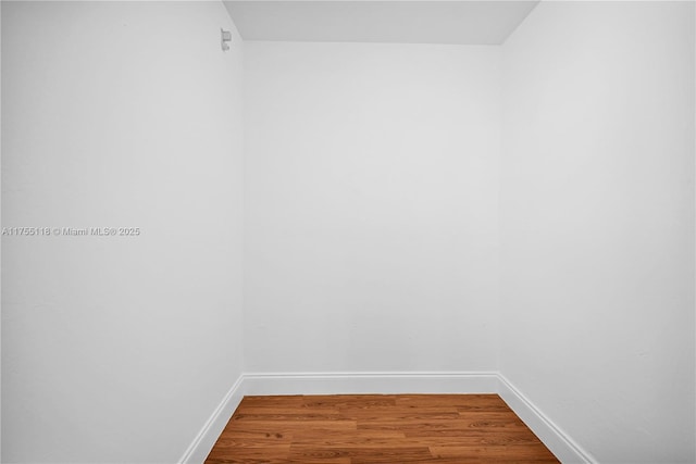 spare room featuring baseboards and wood finished floors