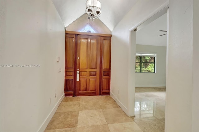 foyer entrance featuring an inviting chandelier, baseboards, and lofted ceiling