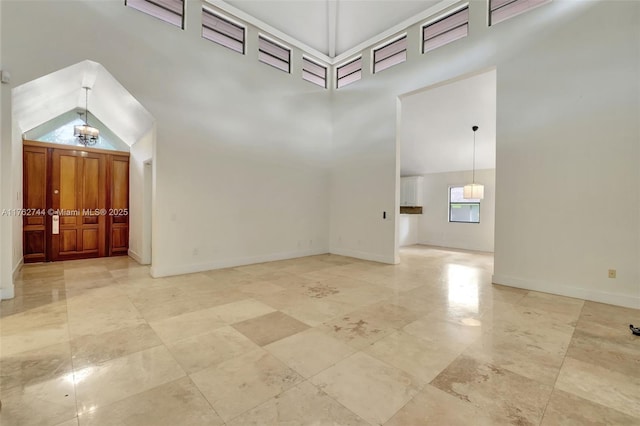 empty room featuring high vaulted ceiling and baseboards