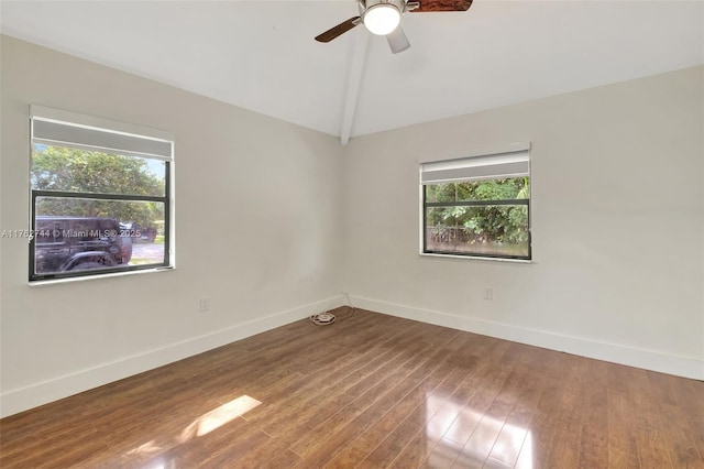 spare room featuring wood finished floors, a healthy amount of sunlight, baseboards, and vaulted ceiling