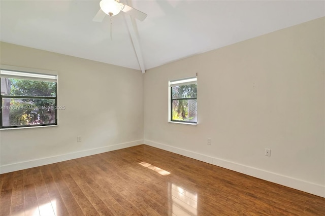 empty room featuring baseboards, wood finished floors, and vaulted ceiling with beams