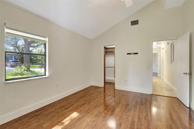 unfurnished bedroom featuring a spacious closet, visible vents, baseboards, and hardwood / wood-style floors