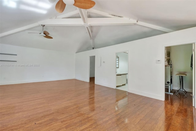 unfurnished room featuring baseboards, vaulted ceiling with beams, a ceiling fan, and wood finished floors