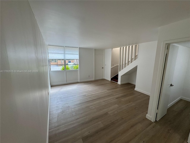 empty room with stairway, baseboards, and wood finished floors