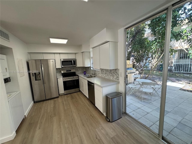 kitchen featuring backsplash, stainless steel appliances, light wood-style floors, and a sink