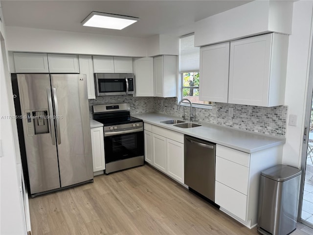 kitchen featuring a sink, tasteful backsplash, light wood-style floors, appliances with stainless steel finishes, and light countertops