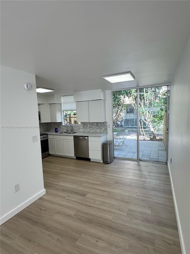 kitchen with tasteful backsplash, light wood finished floors, appliances with stainless steel finishes, white cabinetry, and a sink