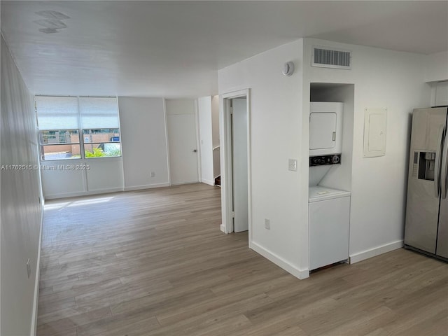 spare room with visible vents, light wood finished floors, baseboards, and stacked washer / dryer