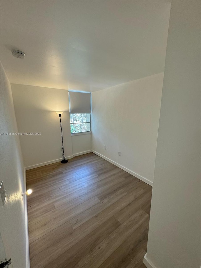 unfurnished room with baseboards and wood finished floors