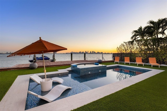 view of swimming pool with a yard, a water view, a boat dock, and a pool with connected hot tub